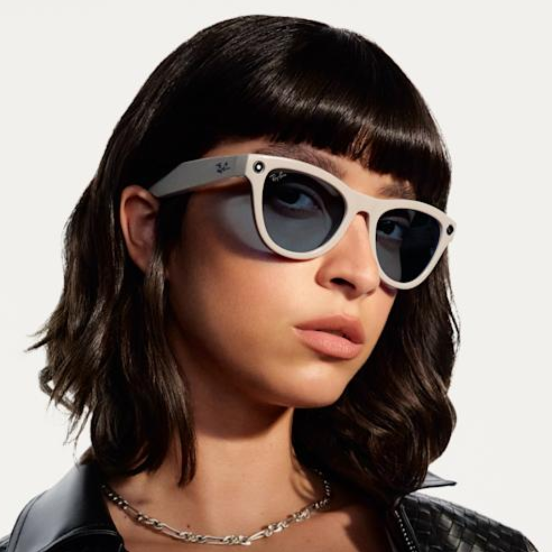 Primer plano de mujer con cabello oscuro y chaqueta de cuero usando gafas inteligentes Ray-Ban Meta Wayfarer blancas.